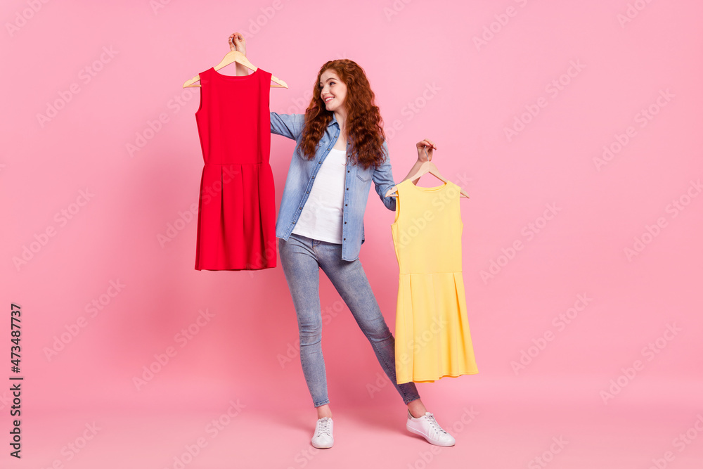 Full length photo of charming happy positive young woman hold hands dress choose isolated on pink color background Full length photo of charming happy positive young woman hold hands dress choose isolated on pink color background