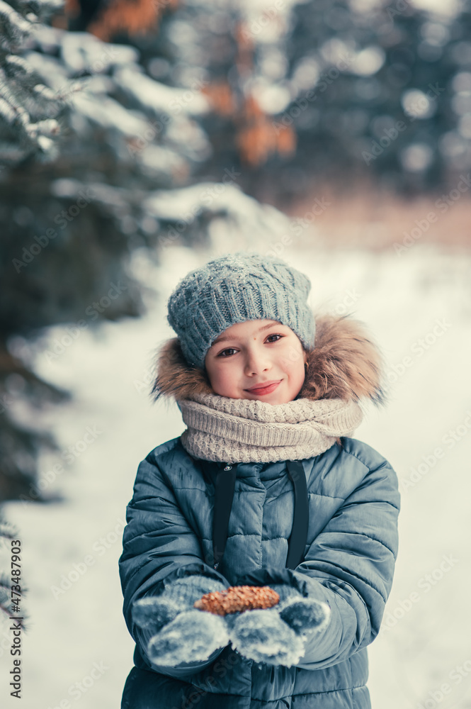 Happy girl in a winter fir forest holding a pine cone in her hands Happy girl in a winter fir forest holding a pine cone in her hands