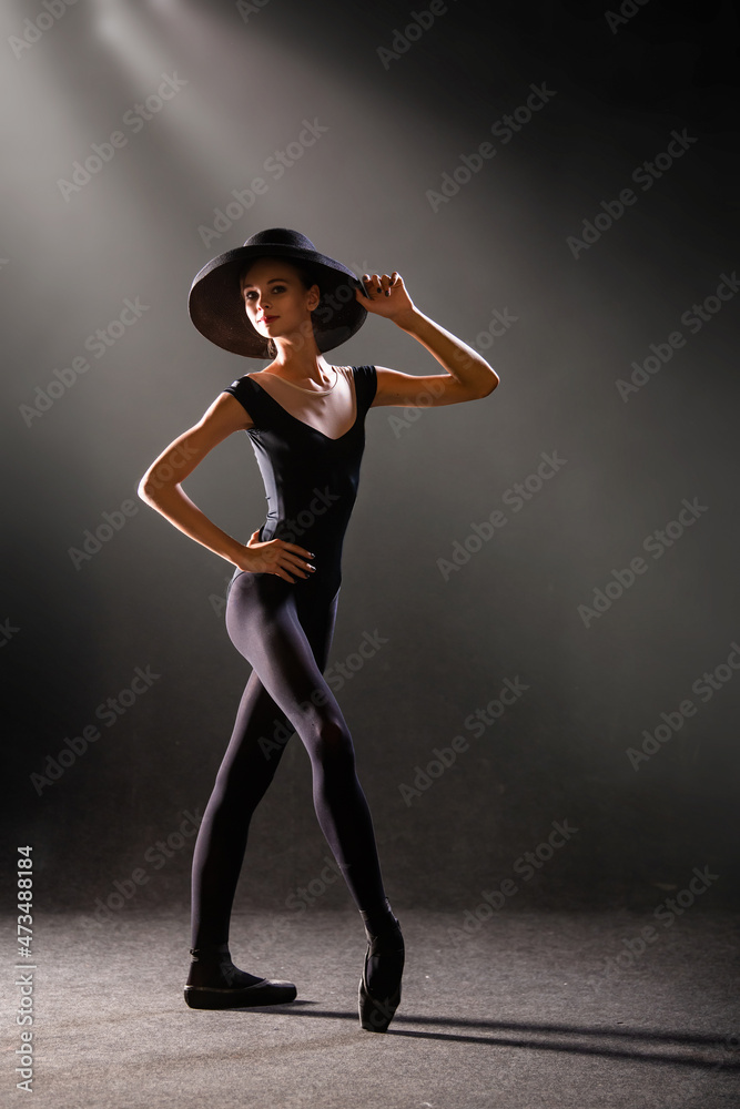 ballerina in tight-fitting suit is dancing on black background on pointe shoes, silhouette is illuminated by sources of color. ballerina in tight-fitting suit is dancing on black background on pointe shoes, silhouette is illuminated by sources of color.