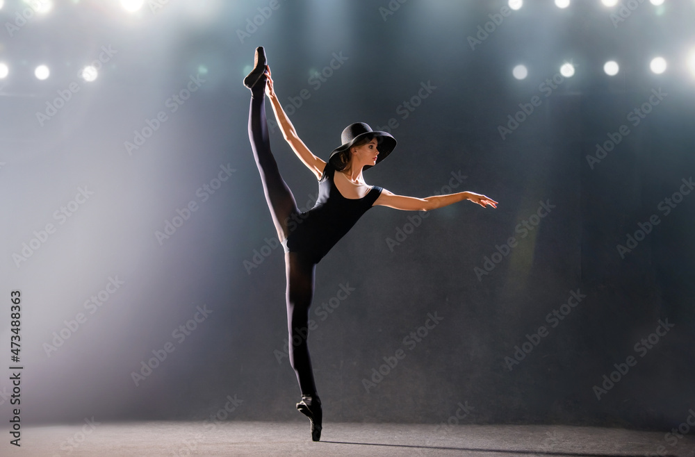 ballerina in tight-fitting suit is dancing on black background on pointe shoes, silhouette is illuminated by sources of color.