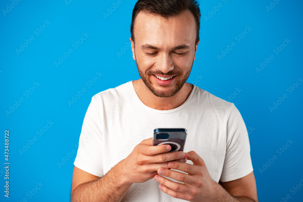 Man looking at phone, standing isolated on blue background Man looking at phone, standing isolated on blue background