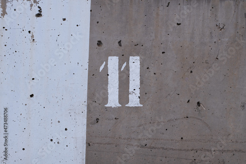 cement wall with two shades of grey and the number 11 painted on it