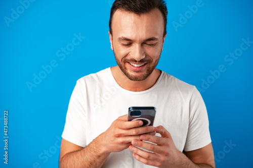 Man looking at phone, standing isolated on blue background © fotofabrika