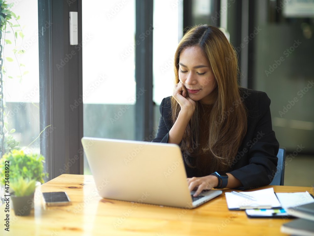 Business woman using laptop computer at her workspace.