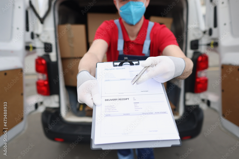 Man in uniform and face mask give delivery receipt paper to receiver to sign