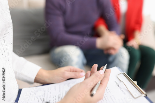 Doctor hold clipboard with patient medical history paper for couple