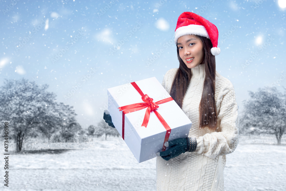 Asian woman with winter gloves and Santa hat holding white gift box Asian woman with winter gloves and Santa hat holding white gift box