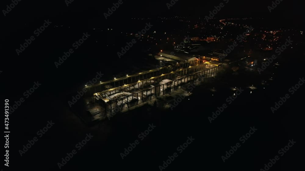 Aerial view of plywood factory at night. Big wood repository. City lights