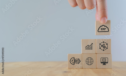 Cloud ERP service concept. Enterprise resources planning business and technology concept. Hand puts ERP business management software as cloud computing service with working on cloud icon on wood cubes photo