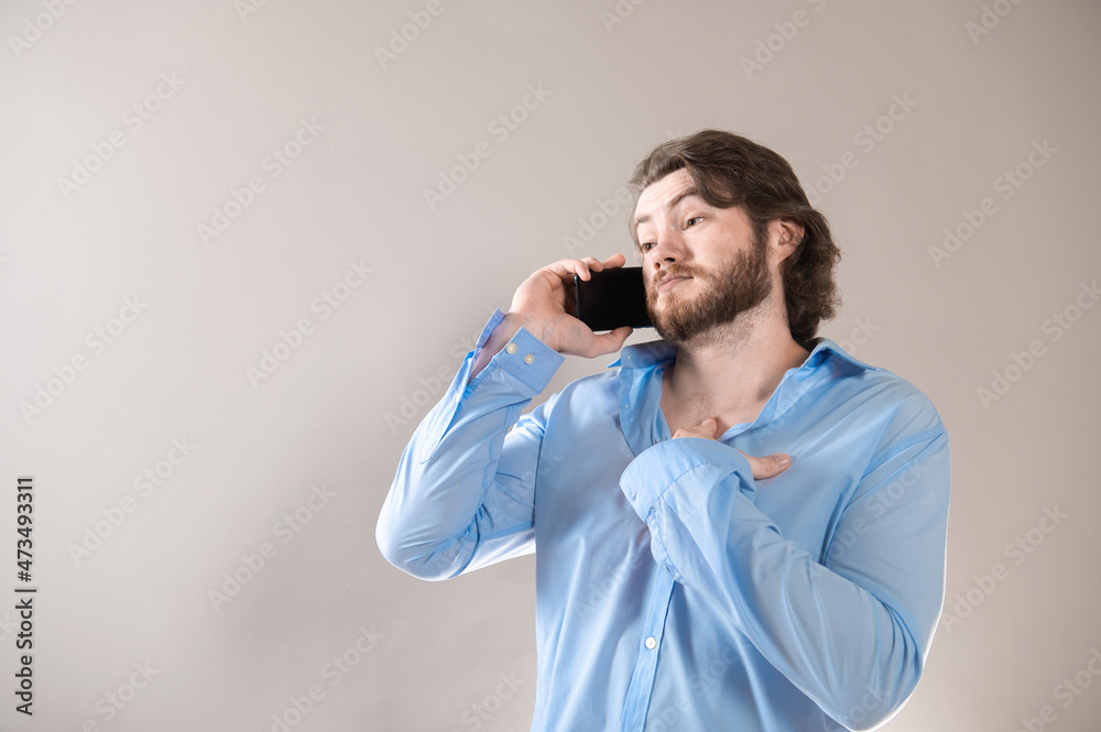 Young bearded man having call and talking on smartphone with pleasure isolated over grey background Young bearded man having call and talking on smartphone with pleasure isolated over grey background