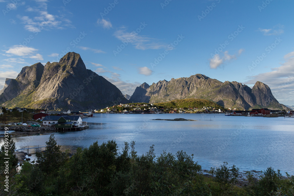 sunny day at reine Lofoten islands norway with blue sky and tiny clouds, fishermen village with huge mountains in a fjord sunny day at reine Lofoten islands norway with blue sky and tiny clouds, fishermen village with huge mountains in a fjord