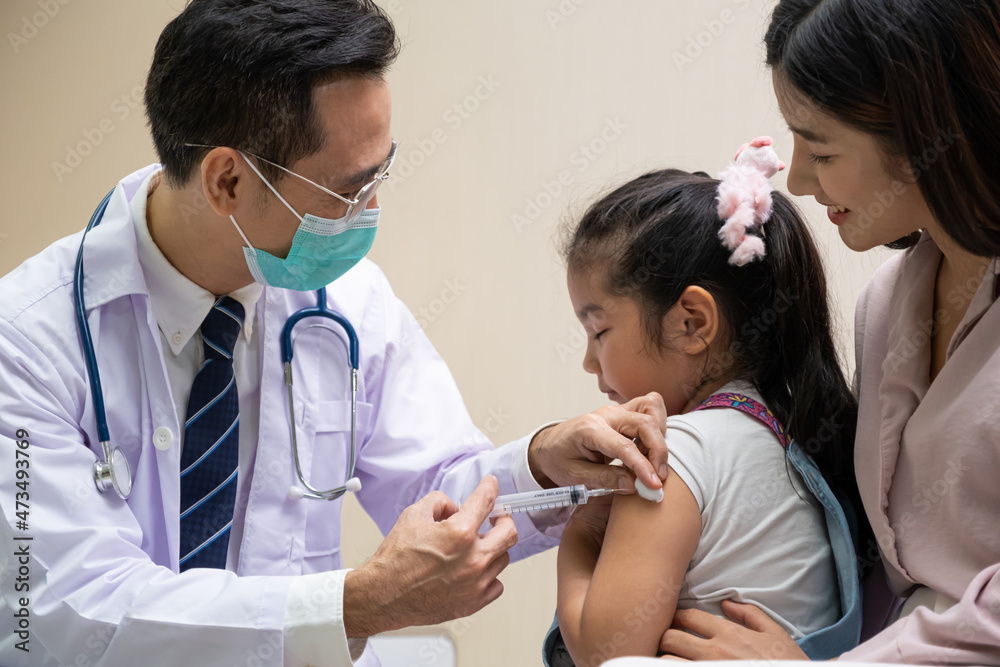 Young Asian girl get medical vaccine injection from the doctor with her mother sit and hold to support. Medical service for young people, kids. Young Asian girl get medical vaccine injection from the doctor with her mother sit and hold to support. Medical service for young people, kids.