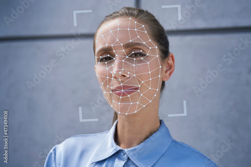 Businesswoman with facial recognition biometrics in front of wall photo