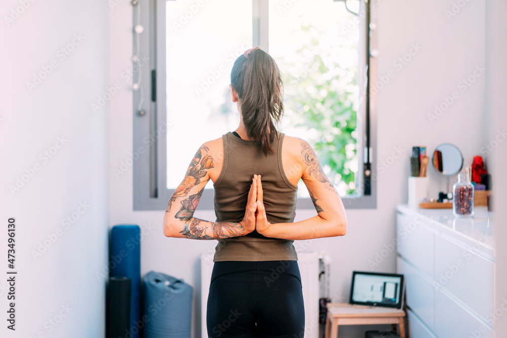 Woman with hands clasped behind back practicing yoga at home Woman with hands clasped behind back practicing yoga at home