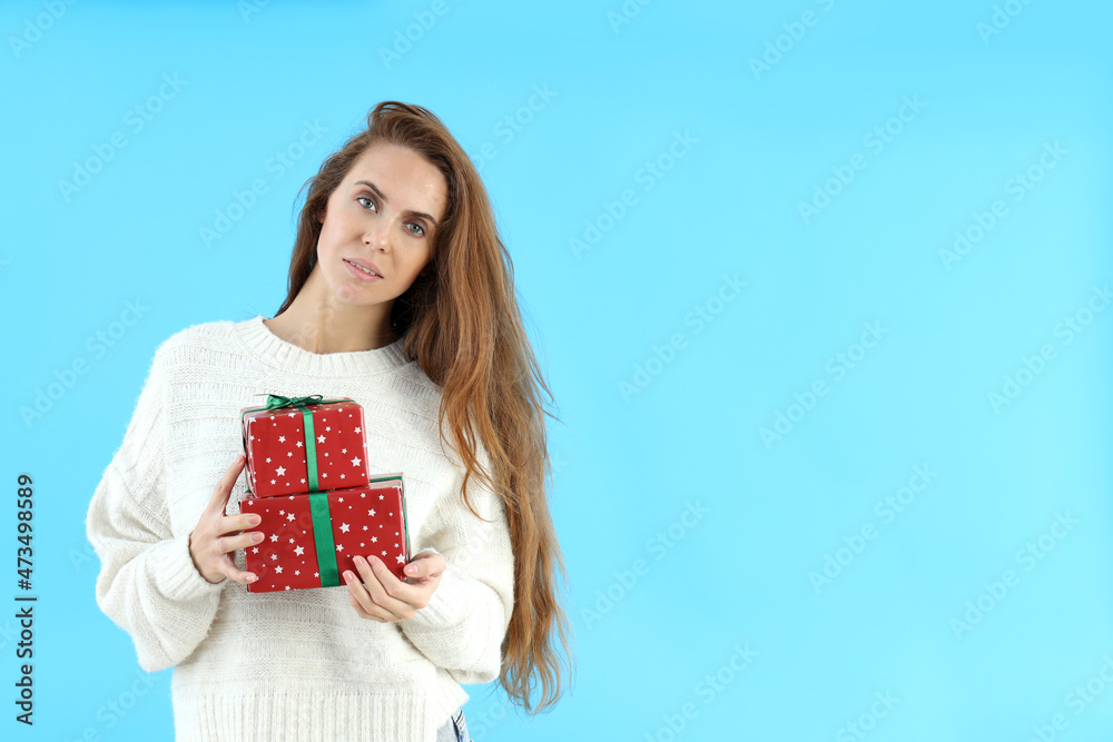 Attractive woman holds gift boxes on blue background Attractive woman holds gift boxes on blue background