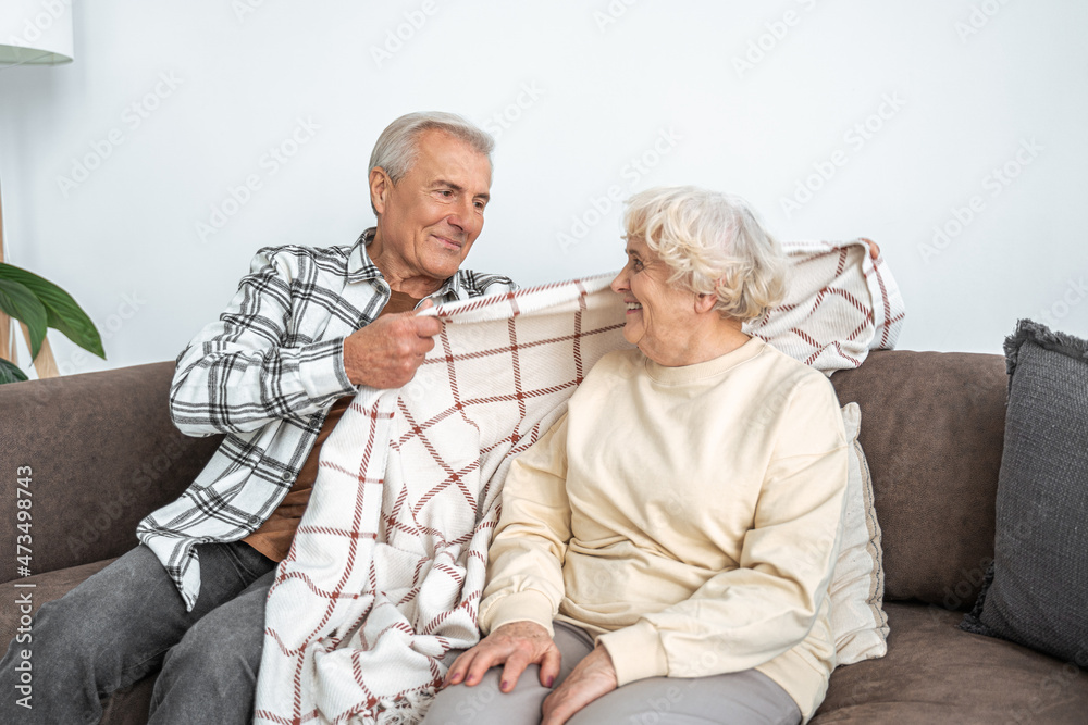 Joyful mature man and woman resting on couch at home
