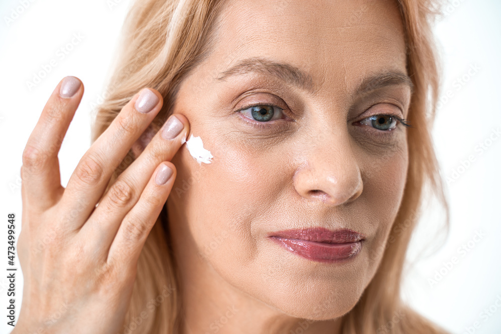 Gorgeous retirement female person with moisturizing cream on her face on white background Gorgeous retirement female person with moisturizing cream on her face on white background