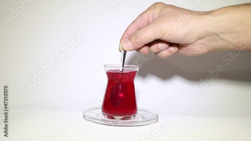 In the cafe, a man's hand mixes the sugar in the tea in slow motion.