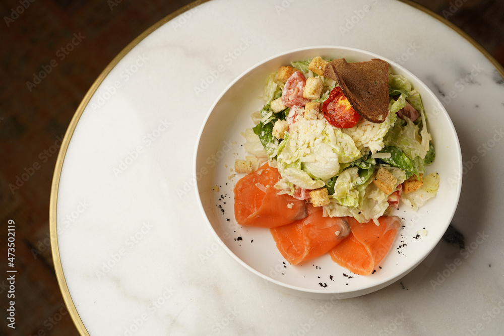 Caesar salad with salmon fish on white bowl Caesar salad with salmon fish on white bowl