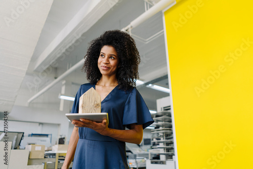Female real estate agent holding digital tablet and house model in agency