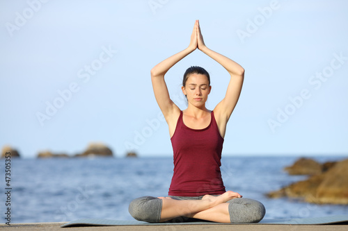 Front view of a woman doing yoga exercise on the beach