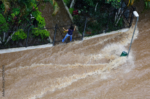 Obraz na plátně Woman try to cross a flooded avenue during an extremely heavy rain in downtown Sao Paulo, Brazil