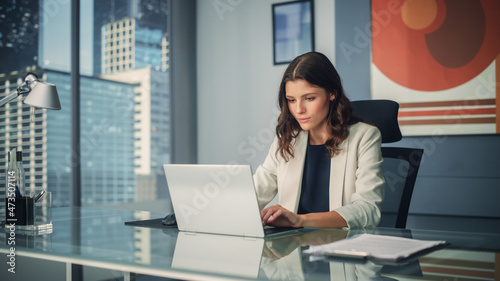 Portrait of Young Successful Caucasian Businesswoman Sitting at Desk Working on Laptop Computer in City Office. Ambitious Corporate Manager Plan Investment Strategy for e-Commerce Project.