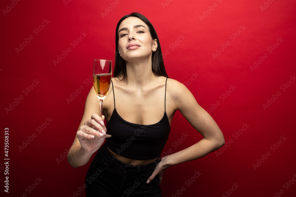 Beautiful brunette with a glass of champagne on a red background Beautiful brunette with a glass of champagne on a red background