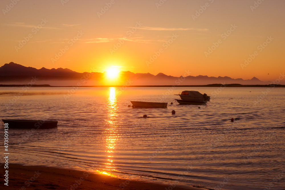 Golden Sunrise over the lagoon with the distant view of mountains and fishermen boats Golden Sunrise over the lagoon with the distant view of mountains and fishermen boats