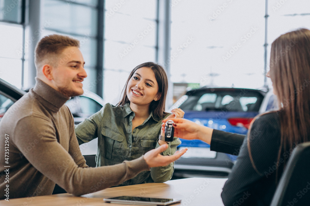 Fototapeta premium Young couple talking to a sales person in a car showroom