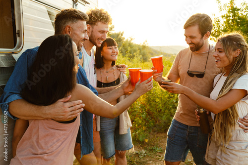 Multiracial friends drinking beverages during picnic by trailer