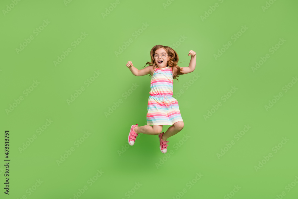 Full length body size photo small girl jumping up gesturing like winner isolated pastel green color background Full length body size photo small girl jumping up gesturing like winner isolated pastel green color background