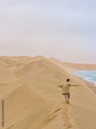 person walking on the sand dunes in the sandwich harbor in Namibia 