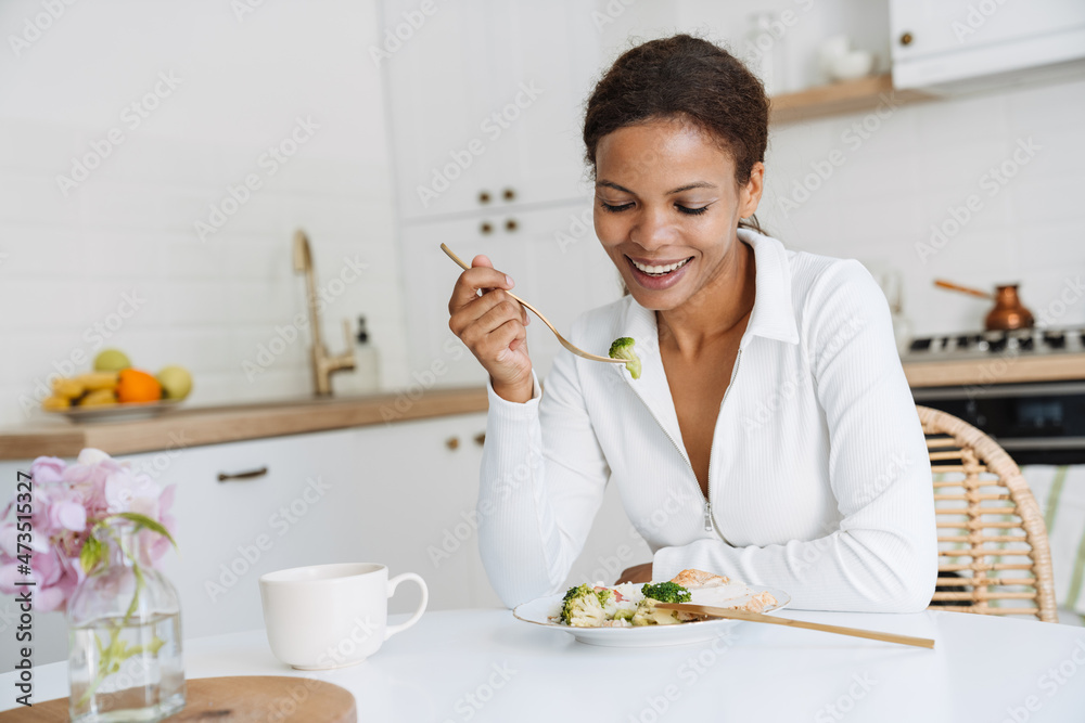Young black woman smiling while having lunch at home Young black woman smiling while having lunch at home