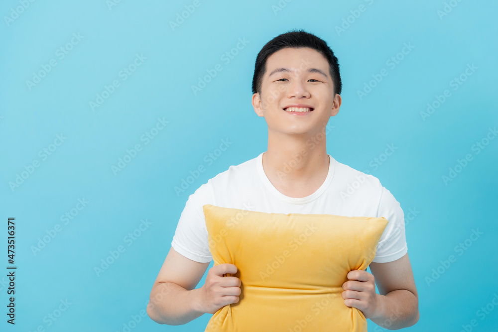 man's hugging a yellow cushion isolated on light blue background man's hugging a yellow cushion isolated on light blue background