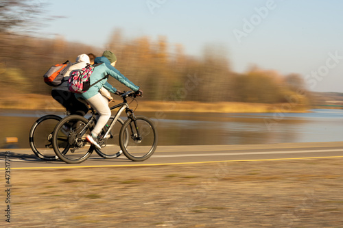 Photo of two people on bicycles on the street in the park against the blurred background of the forest in autumn. Sport
