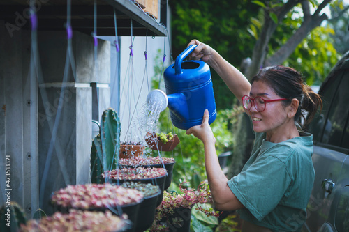 beautiful asian woman watering colorful plant in hanging pot photo