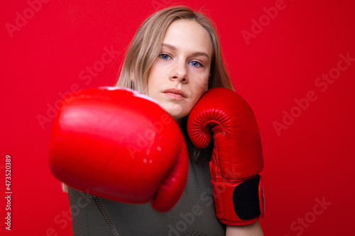 Sporty young woman in red boxing gloves practicing punches