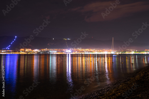 Night city with lights and mountains by the sea.