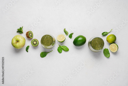 Green smoothie in glasses and vegetables and fruits for preparing healthy drink. Raw vegan juice, top view