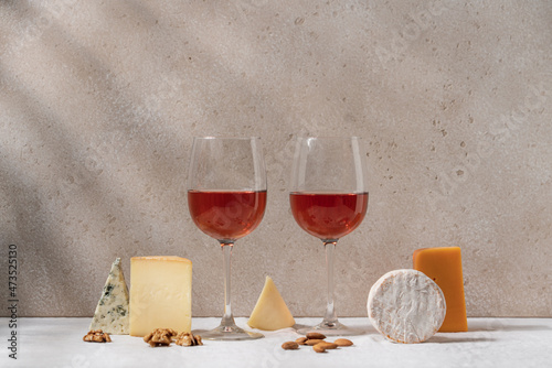 Tableau sur toile Set of rosé wine in glasses on tablecloth covered table with variety of cheeses