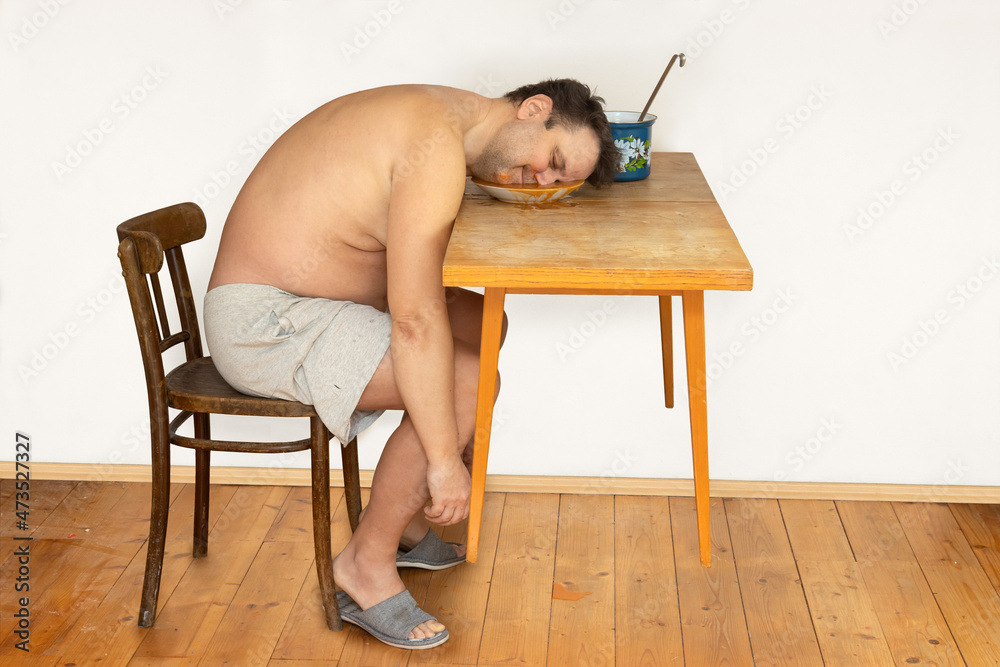 Φωτογραφία The happy fat man with his head in a plate full of soup on a levitating table