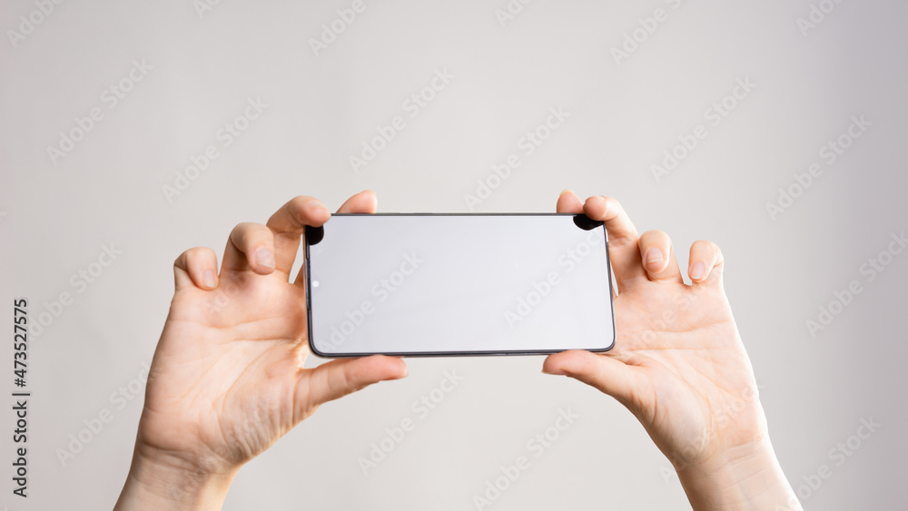 Use your smartphone horizontally, take panoramic photos, or watch videos. Phone in women's hands. Layout for design, mockup. light grey background Use your smartphone horizontally, take panoramic photos, or watch videos. Phone in women's hands. Layout for design, mockup. light grey background