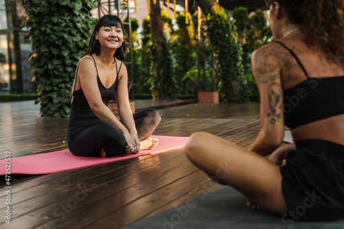 Multiracial two women smiling and talking during yoga practice