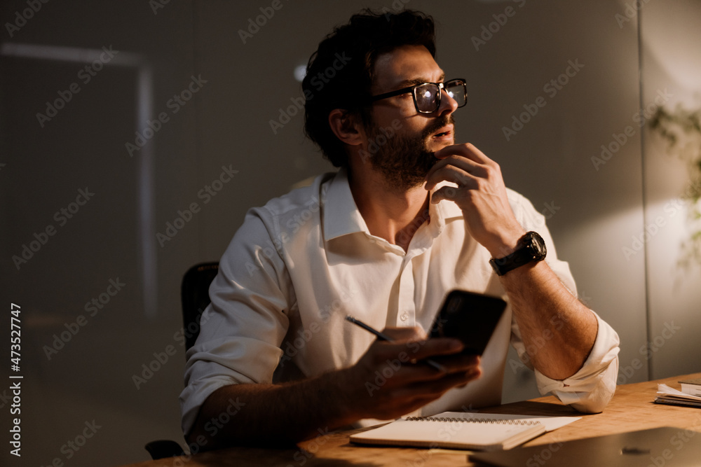 White bearded man using cellphone while working at office White bearded man using cellphone while working at office