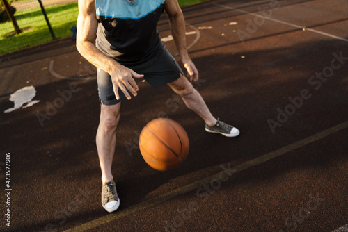 White man playing basketball while working out on sports ground