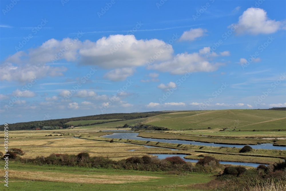 Cuckmere River and valley seen with blue skies and fluffy white clouds (East Sussex, United Kingdom) 