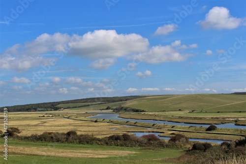 Cuckmere River and valley seen with blue skies and fluffy white clouds (East Sussex, United Kingdom) 