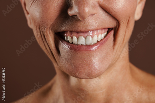 Senior shirtless woman smiling while posing on camera