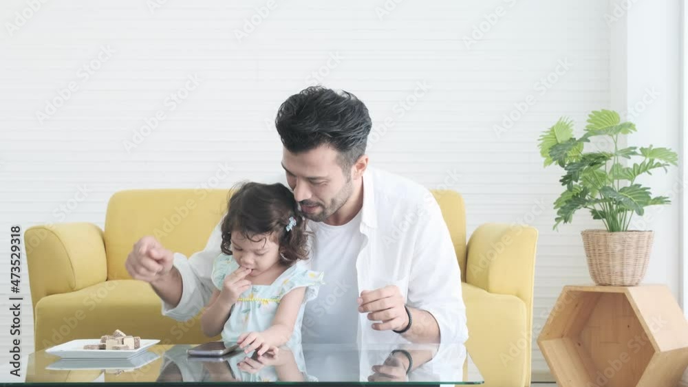 Father plays with daughter on phone with delicious snacks in the room. Father plays with daughter on phone with delicious snacks in the room.